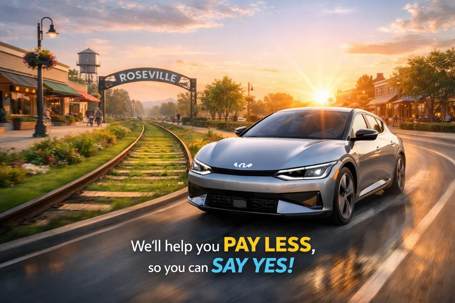 A silver Kia EV6 driving past historic Roseville railroad tracks during a bright sunrise.